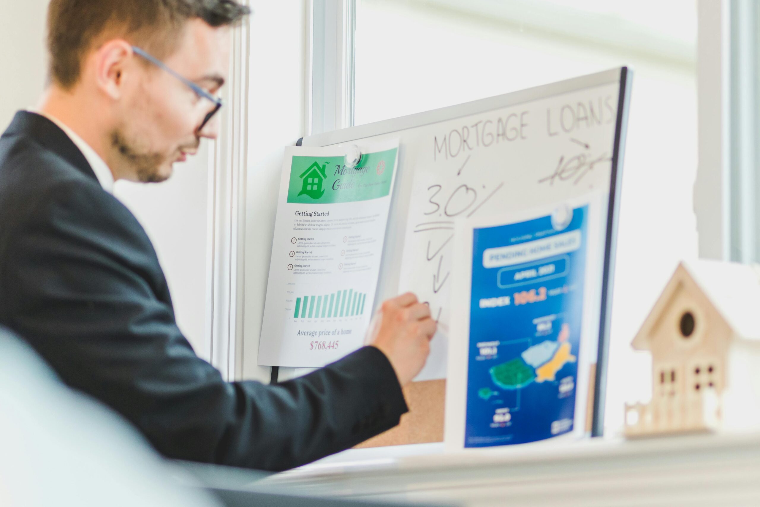 Mortgage advisor explaining loan details using charts and documents on a whiteboard.